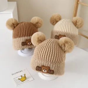 Warm knit baby earflap hat with dual pom-poms and cartoon bear patch for winter