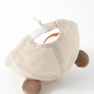 Detail of soft cream plush pet bear hat with brown pom-poms and adjustable velcro closure