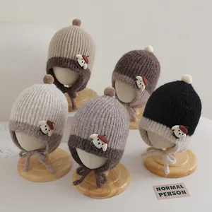 Detailed view of knitted earflap hats in neutral colors with cute puppy patches