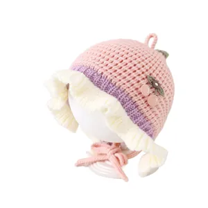 Cuffietta in maglia rosa per neonata con bordi smerlati bianchi e decorazione a ciliegia