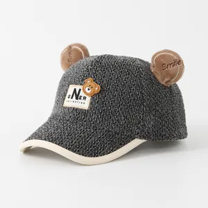 Detail view of a grey fleece kids baseball cap with plush bear ears and Smile embroidery