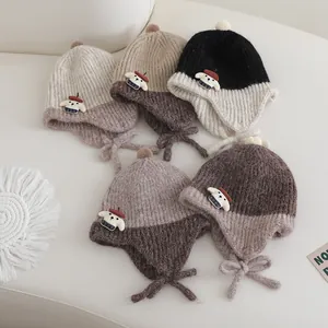 Detail of knitted baby hats with pom-poms and cute bear patches in multiple warm colors