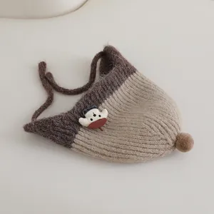 Winter knit baby earflap hat with pom pom and cartoon mushroom in brown tones