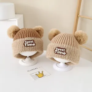Detailed macro view of the thick ribbed knit texture and soft bear ear pom-poms on the baby hat