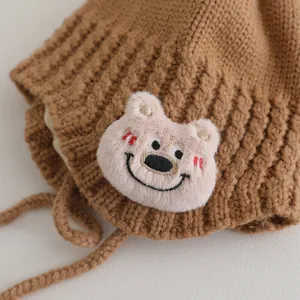 Dettaglio del cappello in maglia per neonati con toppa a orsetto e texture morbida