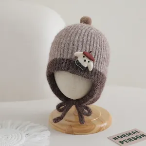 Detailed knit of brown earflap hat with fluffy pompom and cute puppy patch for toddlers