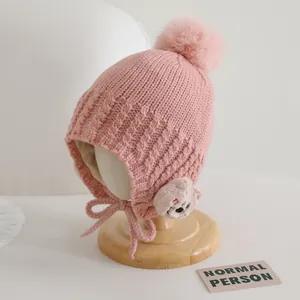 Dettaglio del cappello in maglia rosa per neonati con pompon e fodera interna