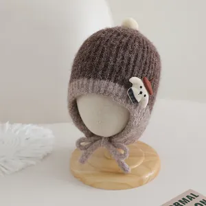 Detailed view of the cozy knitted earmuff hat featuring a cute puppy patch and pom-pom