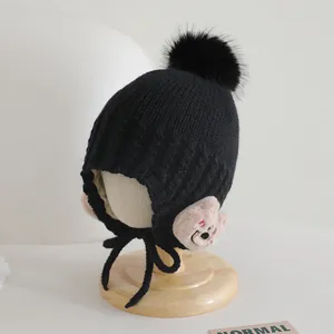 Dettaglio cappello invernale bimbi con paraorecchie a orsetto e pompon in ecopelliccia