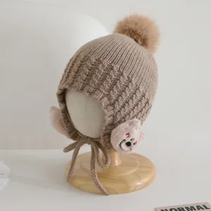 Dettaglio cappello in maglia per bambini con orecchie di orso e un grande pompon morbido
