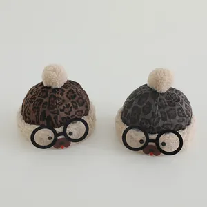 Close-up of leopard print baby hats with soft pom-poms and cute bear faces for winter