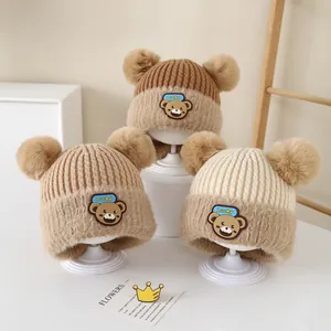 Detailed view of baby knitted hats with fuzzy pom-poms and cute lucky bear embroidery patches