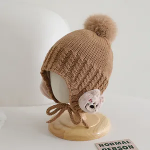Dettaglio della maglia del cappello invernale marrone per bambini con orsetto e paraorecchie