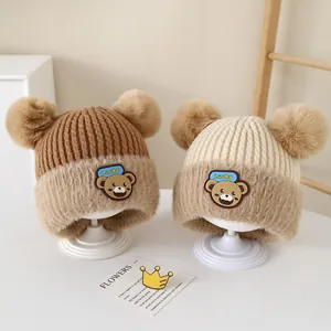 Detailed knit of cozy baby bear beanie with plush pom-poms and Lucky embroidery