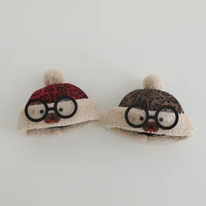 Detailed texture of leopard print baby winter hats with glasses decor and pom-poms