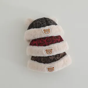 Detail of plush baby beanies with leopard print and cute bear patches in three colors