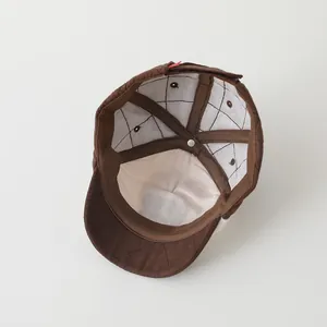 Detail of warm brown quilted baseball cap with cream lining and reinforced stitching