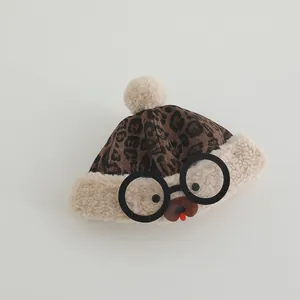 Detail of leopard print baby winter hat with plush pompom and cartoon glasses design