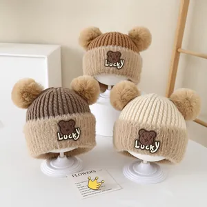 Three warm baby knitted bear hats with fuzzy pom-poms and cute Lucky bear embroidery