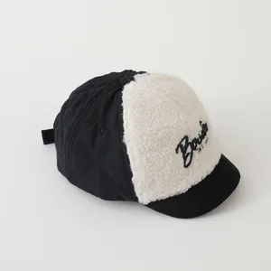 Close-up of quilted fabric and sherpa fleece detail with Bonjour embroidery on baby cap