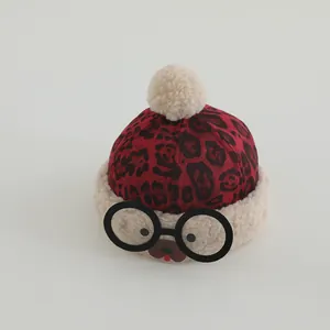 Detail of red leopard print baby winter hat with plush pom-poms and glasses decor