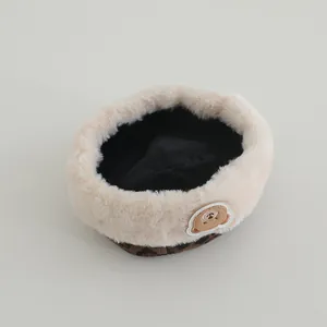 Detailed close-up of warm winter baby hat with bear patch and faux fur trim