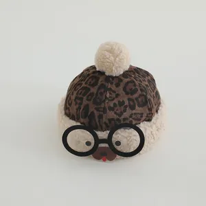 Close-up of fluffy leopard print kids hat with decorative glasses and plush pom-poms
