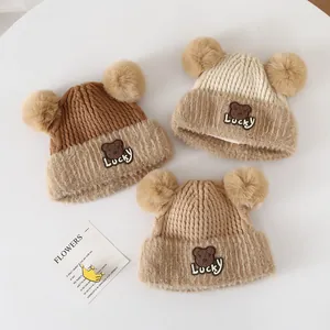 Detailed view of three warm knit bear hats with double pom-poms and furry trim edges