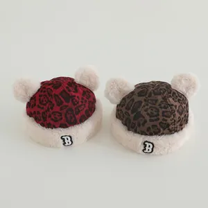 Detail of leopard print baby beanies with white faux fur trim and dual pom-poms