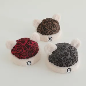 Detailed view of plush leopard print baby hats with white faux fur trim and pom-poms
