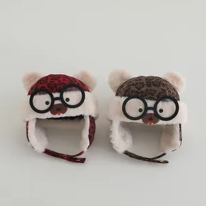 Detail view of leopard print warm kids earflap hat with cute pompom and bear goggles