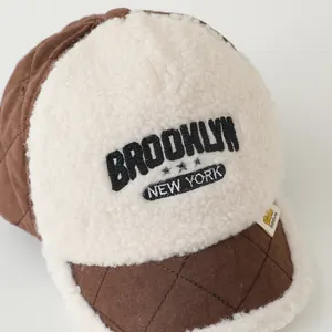Detailed shot of quilted brown fabric and faux shearling with Brooklyn embroidery on cap