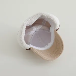 Detail view of winter baby hat featuring warm beige sherpa lining and soft fabric textures