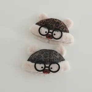 Detail of leopard print baby plush hats with teddy ears and playful puppy glasses design