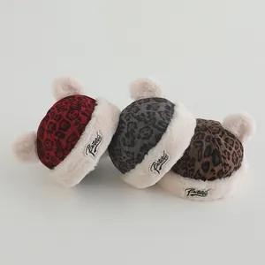 Close-up of leopard print winter beanies with double faux fur pom-poms for toddlers