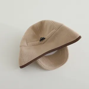 Detail view of beige fleece hat with dark brown piping and adjustable drawstring buckle