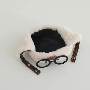 Detail of plush baby earflap hat with leopard print straps and decorative glasses