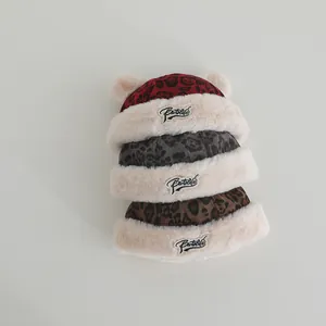 Three leopard print plush baby hats with furry trim and animal ears shown in multiple colors