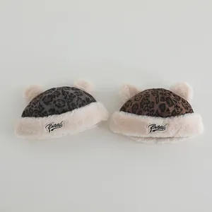 Detail view of leopard print plush beanies with double pom-poms and warm faux fur lining