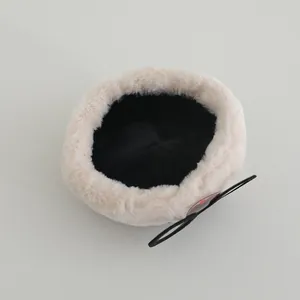 Top view of plush white baby hat featuring a black bow with red button detail