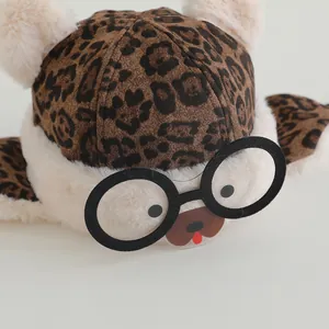 Detail of leopard print plush earflap hat with fluffy pom ears and cartoon glasses