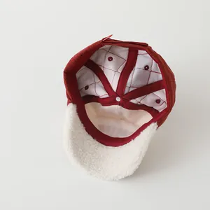 Detailed interior of a quilted burgundy baby cap with soft white sherpa fleece lining