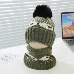 Détail de l'ensemble bonnet et écharpe en tricot vert avec pompon sur un support