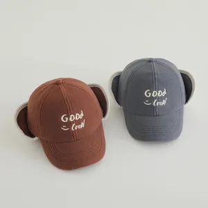 Detail of warm winter earflap hats in brown and gray with Good Luck embroidery