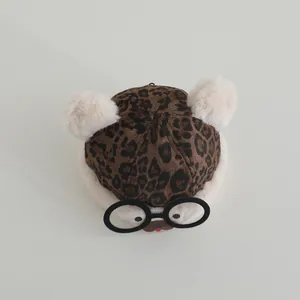 Close-up of fluffy leopard print kids winter hat with decorative glasses and ears