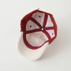 Detail of burgundy baseball cap showing white faux shearling brim and mesh lining