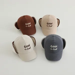 Detail of four plush baseball caps with earflaps and Good Luck embroidery for winter