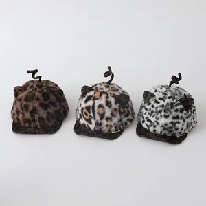 Detailed view of three leopard print plush toddler hats in brown, yellow and grey