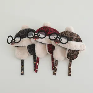 Detailed view of plush leopard print baby trapper hats with pom-pom and bear glasses design
