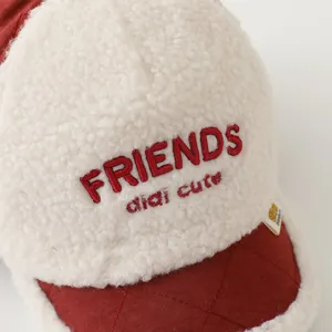 Macro shot of white fleece baby baseball cap with red FRIENDS embroidery and stitched brim
